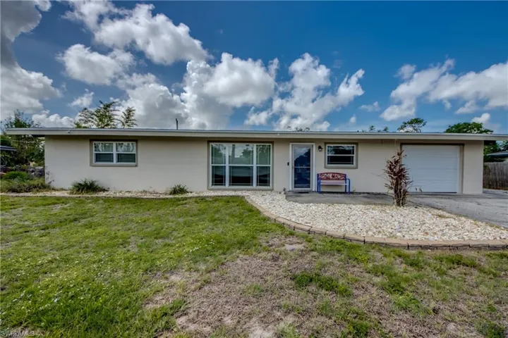 Single story home with stucco siding, a garage, a front yard, and asphalt driveway