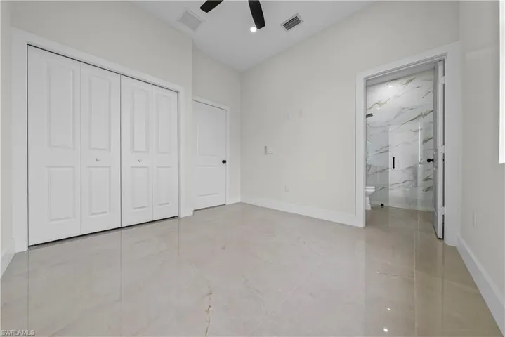 Unfurnished bedroom with a closet, ceiling fan, and light marble finish floors