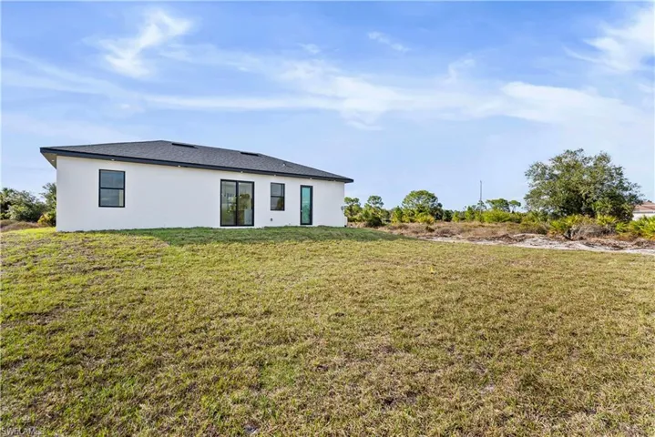 Rear view of property with a lawn and stucco siding