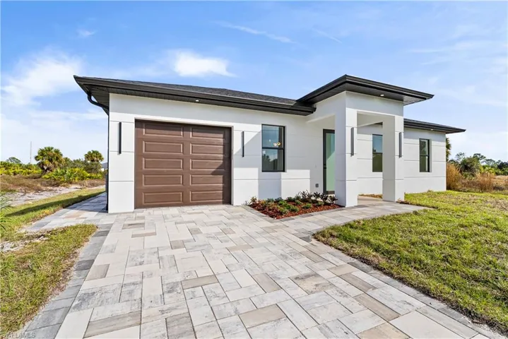 Modern home with stucco siding, a front yard, driveway, and a garage