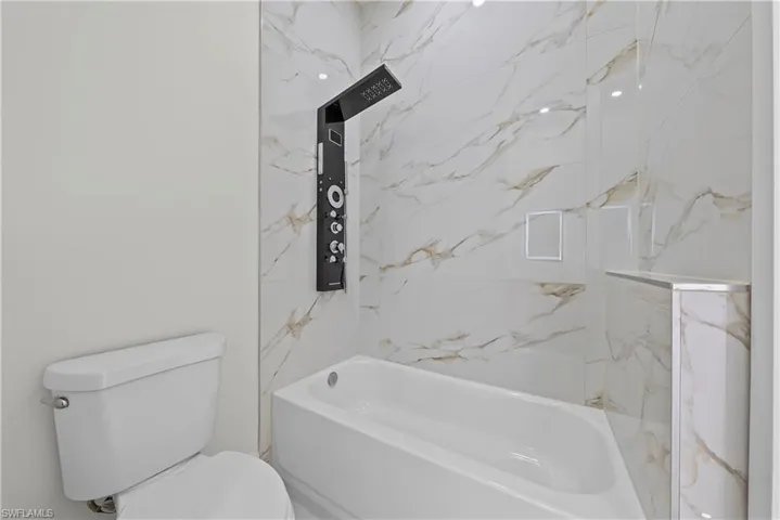Bathroom featuring toilet and washtub / shower combination
