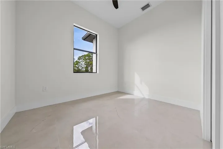 Empty room with lofted ceiling and a ceiling fan