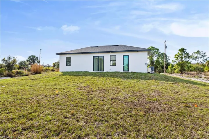 Back of house featuring a lawn and stucco siding