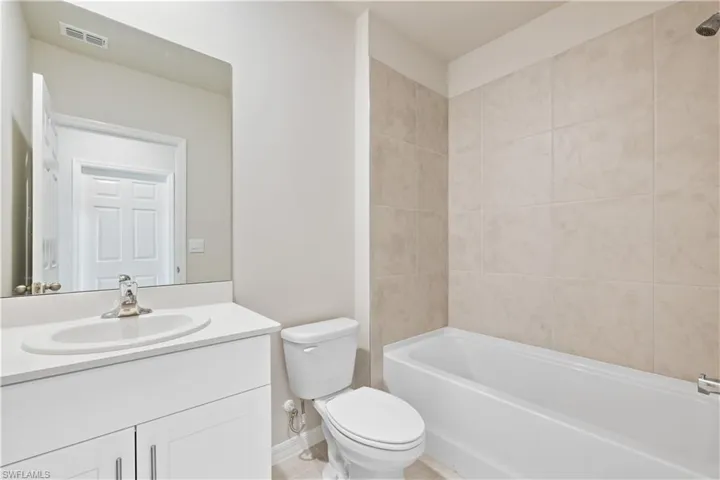 Full bathroom with toilet, tiled shower / bath, vanity, and tile patterned floors