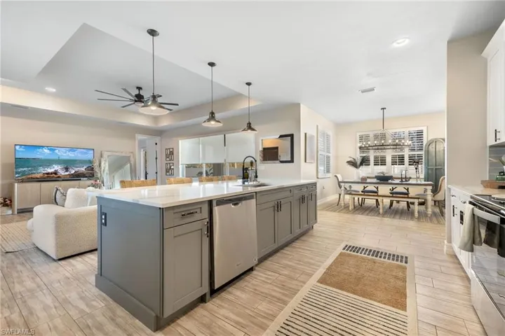 Kitchen with gray cabinetry, pendant lighting, a center island with sink, and appliances with stainless steel finishes