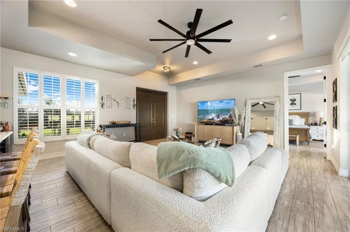 Living room featuring a tray ceiling and ceiling fan