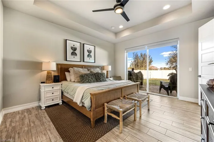 Bedroom featuring access to outside, ceiling fan, and a tray ceiling