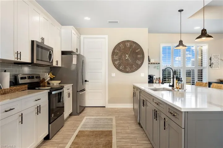 Kitchen featuring white cabinetry, sink, stainless steel appliances, pendant lighting, and gray cabinets