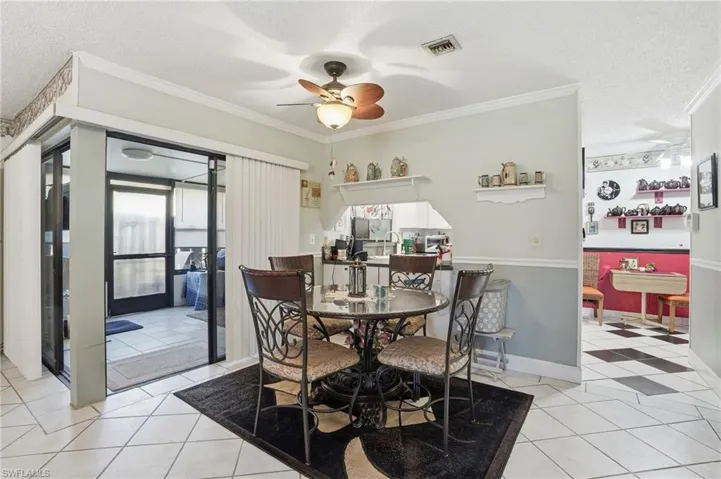 Dining room featuring a ceiling fan, crown molding, light tile