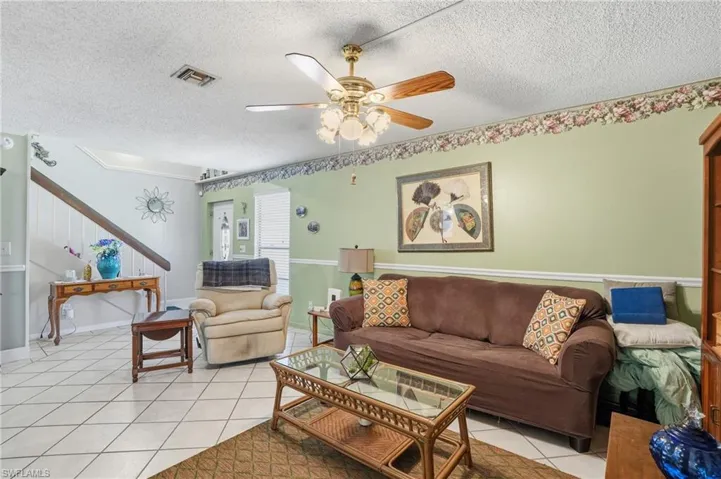Living room featuring light tile, ceiling fan