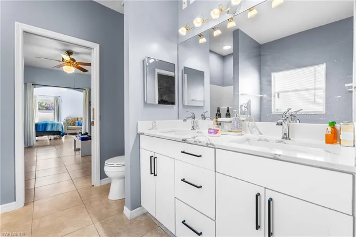 Modern bathroom featuring a dual vanity with white cabinetry, sleek black hardware, and a light-toned countertop