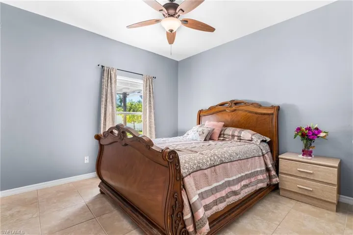 Bedroom featuring tile flooring, a window with exterior visibility, a ceiling fan with integrated lighting, and light blue walls