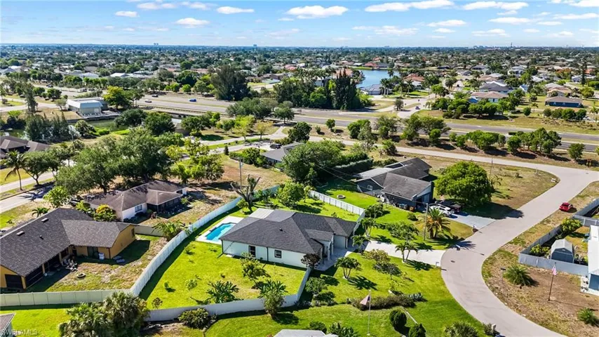 Expansive property featuring a single-story residence with a dark shingle roof, a private swimming pool, and a white privacy fence