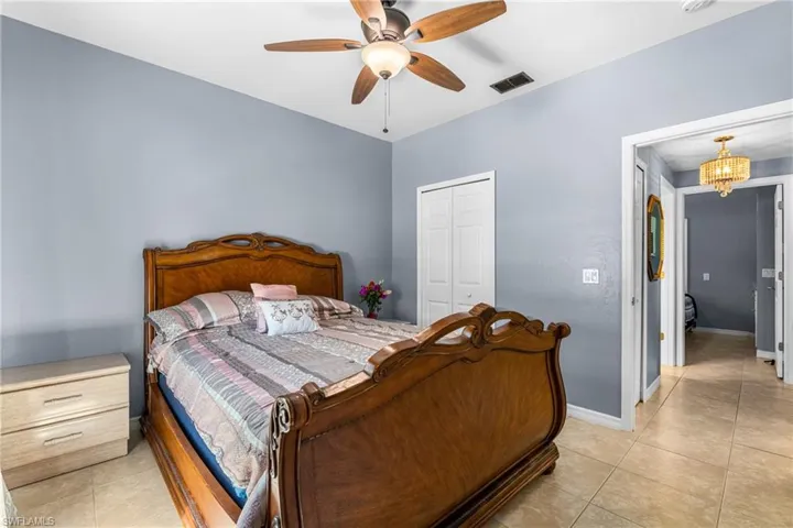 Bedroom featuring a ceiling fan with light fixture, light blue walls, and tiled flooring