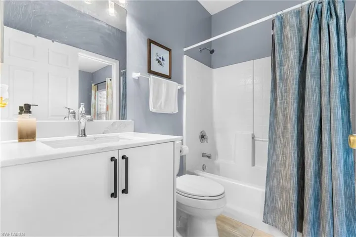 Vanity featuring a white countertop with an integrated sink, white cabinetry with matte black hardware, and a chrome faucet
