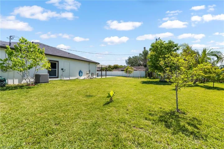 Expansive green lawn with mature trees and a fenced perimeter