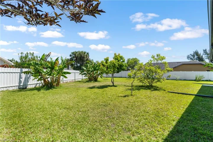 Expansive green lawn with a white privacy fence