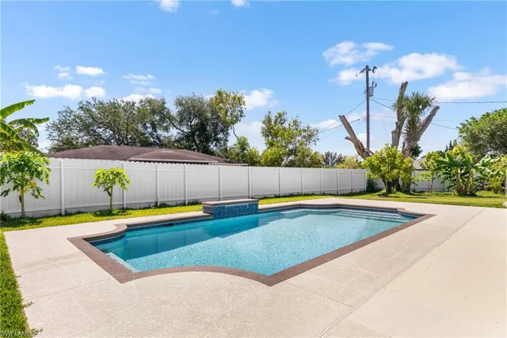 Rectangular inground pool featuring integrated steps and a raised spa with tile detailing