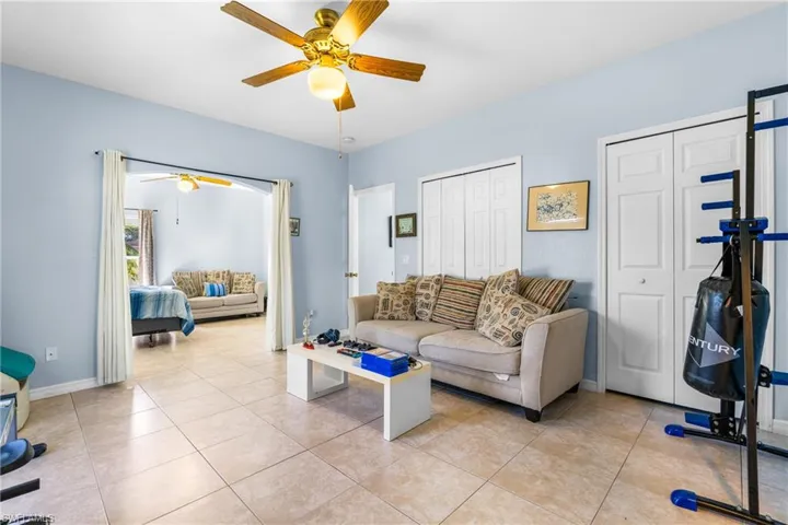 Spacious interior room featuring light-colored tile flooring and a ceiling fan with integrated lighting