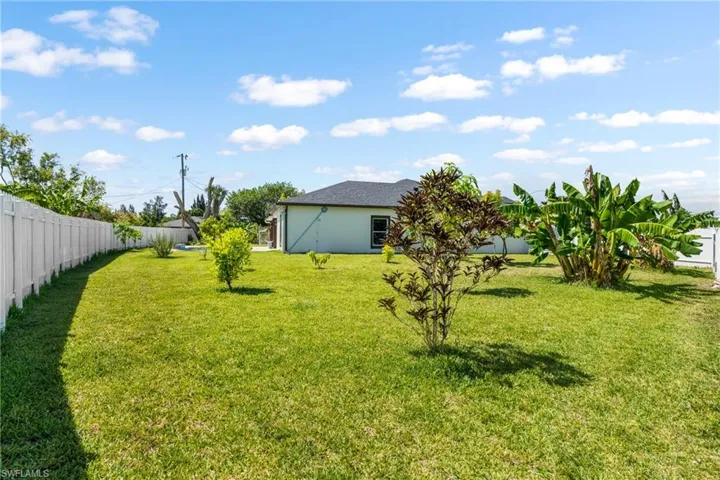 Expansive green lawn with a white privacy fence