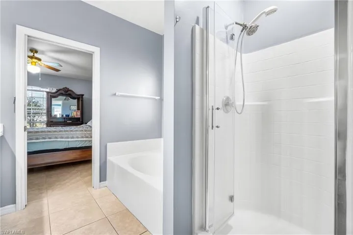 Bathroom featuring a glass-enclosed shower, built-in soaking tub, and tile flooring