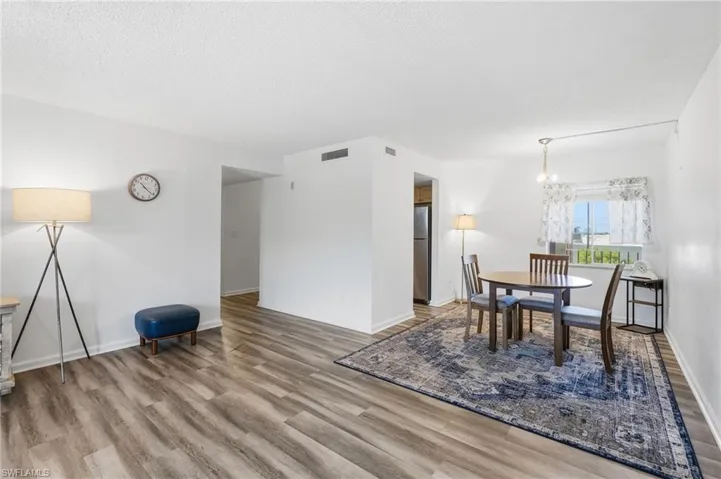 Open-concept living space featuring wood-finish flooring throughout, white painted walls, and a dropped ceiling