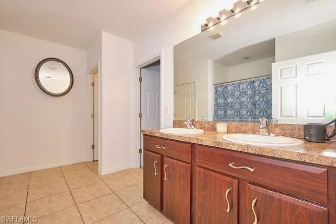 Bathroom featuring double vanity, a shower with curtain, and light tile patterned flooring