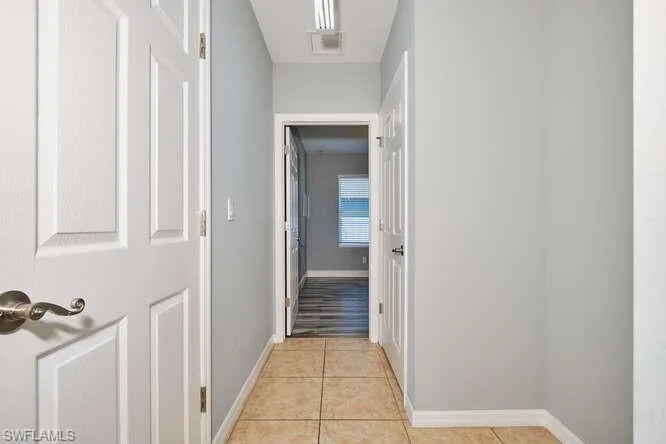 Hallway with baseboards and light tile patterned flooring