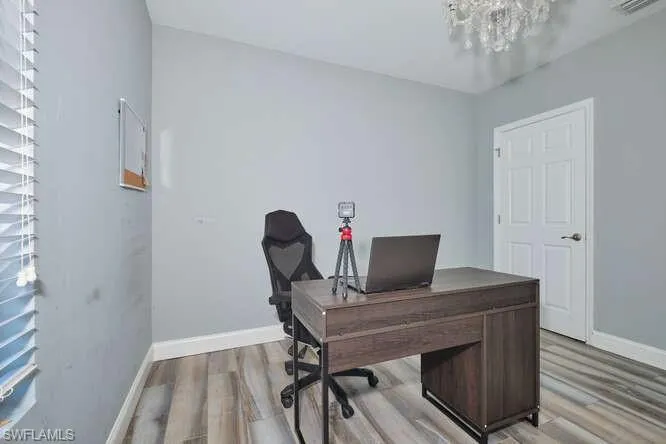 Office area featuring light wood finished floors and a chandelier