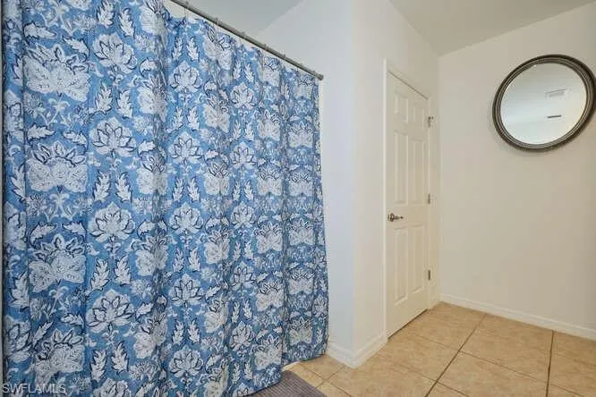 Full bath with a shower with curtain and tile patterned flooring