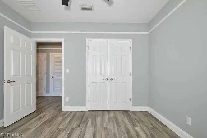 Unfurnished bedroom featuring a closet, wood finished floors, and a ceiling fan