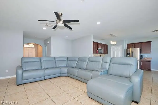 Living area featuring light tile patterned flooring, a ceiling fan, arched walkways, and recessed lighting