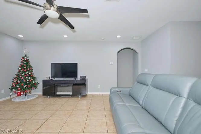Living room featuring arched walkways, ceiling fan, recessed lighting, and light tile patterned floors