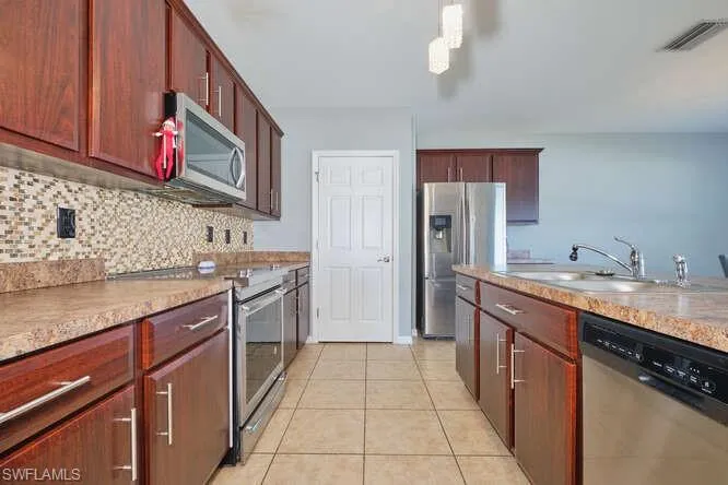 Kitchen featuring stainless steel appliances, light countertops, light tile patterned flooring, and tasteful backsplash
