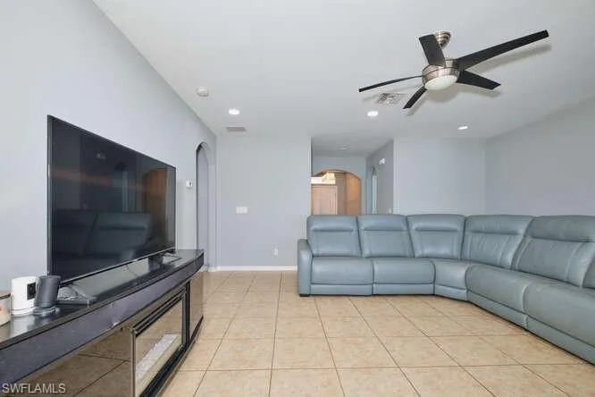Living room featuring light tile patterned flooring, recessed lighting, arched walkways, and ceiling fan