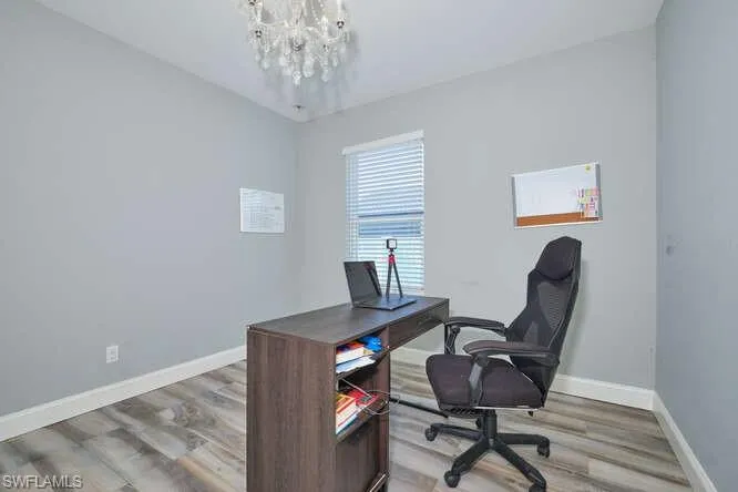 Home office featuring a chandelier and light wood-type flooring