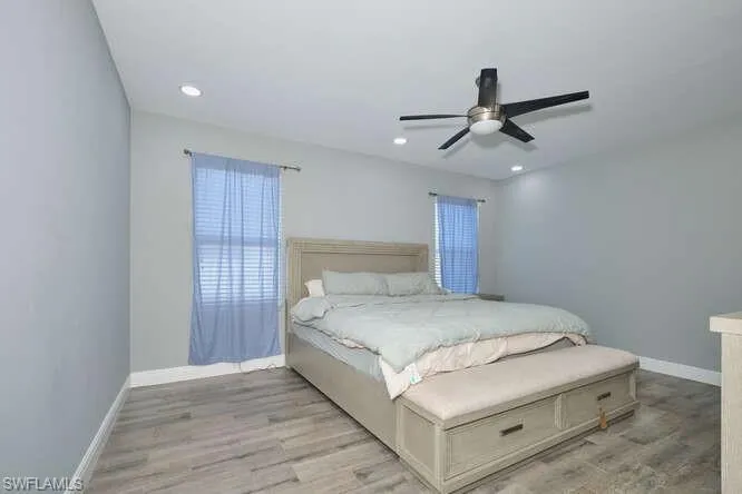 Bedroom with light wood-style floors, ceiling fan, and recessed lighting
