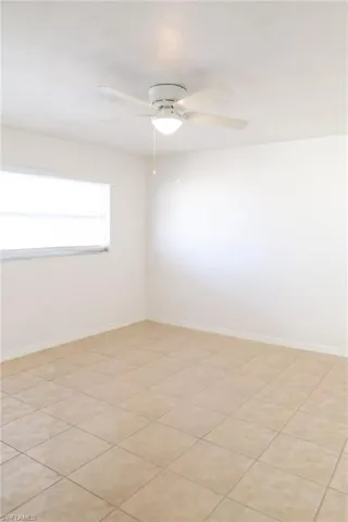 Empty room with ceiling fan and light tile patterned floors