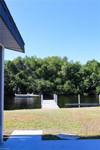 View of green lawn with a boat dock and a water view