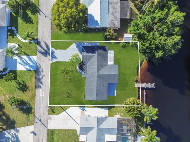 Aerial view of property and surrounding area with a nearby body of water and property boundaries highlighted
