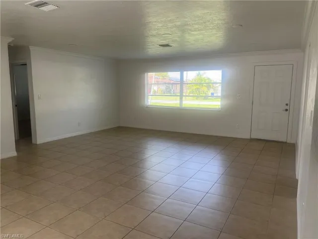 Unfurnished room featuring crown molding, a textured ceiling, and light tile patterned flooring