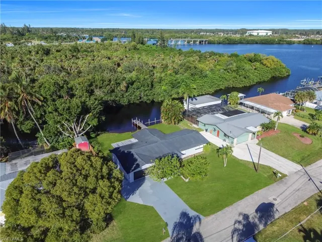 Aerial perspective of suburban area featuring a nearby body of water and a tree filled landscape