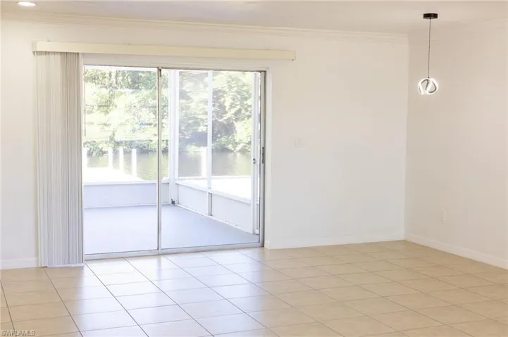 Empty room featuring light tile patterned floors, crown molding, and a water view