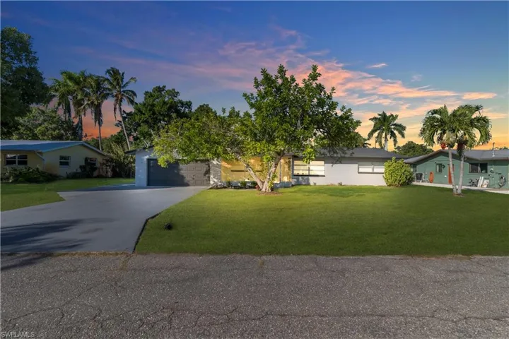 View of front of house with driveway and a lawn