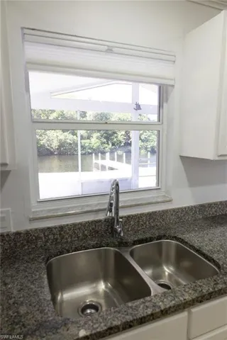 Kitchen view of white cabinetry, nearby water, and dark stone countertops