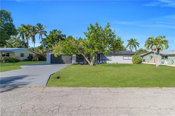 View of front facade featuring driveway, a front yard, and an attached garage