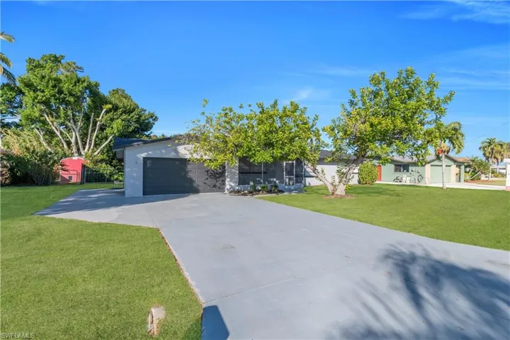 View of front of house with a front lawn, a garage, driveway, and stucco siding