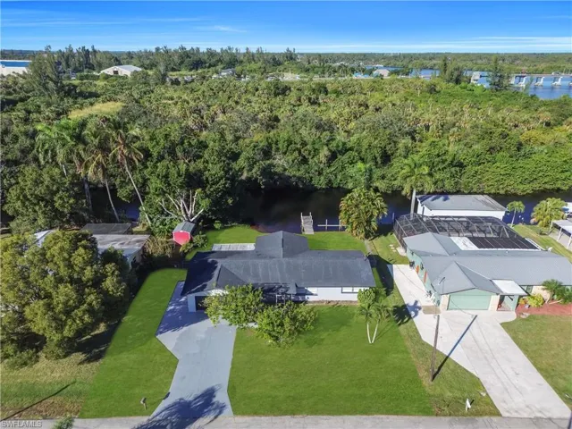 Aerial view of property and surrounding area featuring a nearby body of water and a tree filled landscape