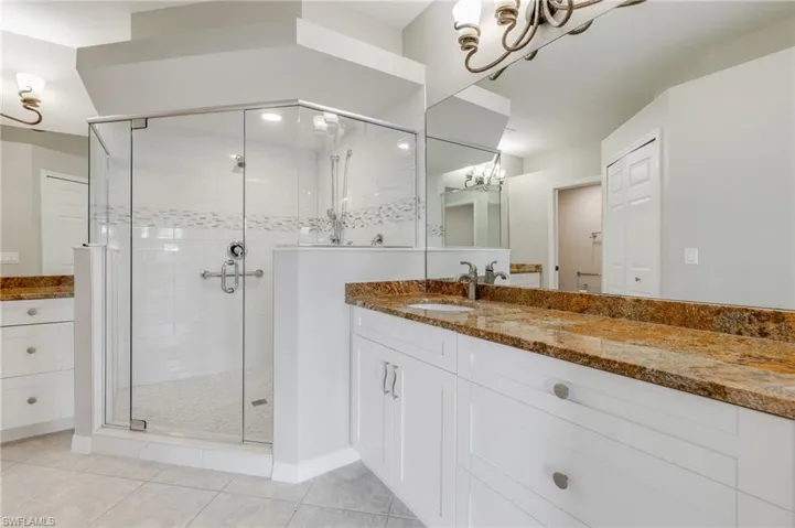 Bathroom with a chandelier, vanity, a stall shower, and light tile patterned floors