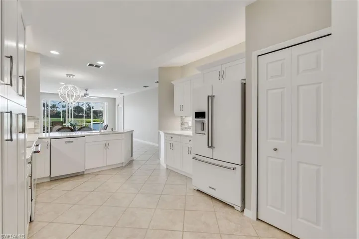 Kitchen with white appliances, white cabinets, light tile patterned flooring, recessed lighting, and backsplash